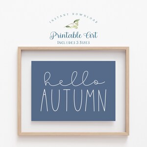May include: A printable art print with the text "hello autumn" in white script on a blue background. The print is framed in a light wood frame.