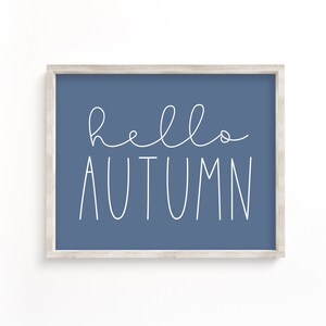 May include: A framed print with a blue background and white text that says "hello autumn".