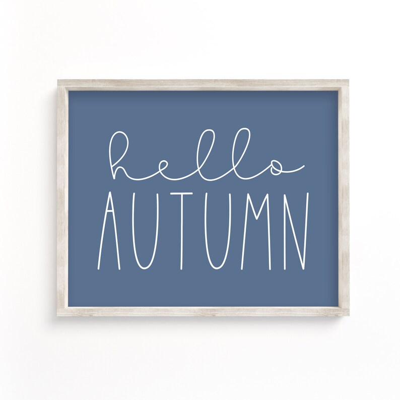 May include: A framed print with a blue background and white text that says "hello autumn".