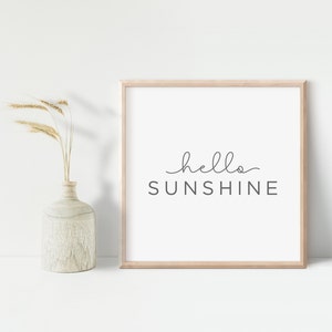 May include: A framed print with a white background and the text "hello sunshine" in a cursive font.