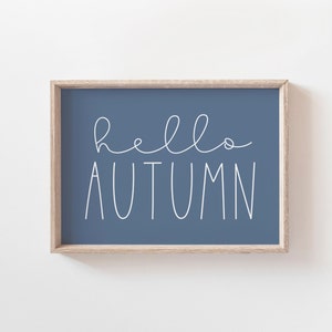 May include: A framed print with the text "hello autumn" in white script on a blue background.