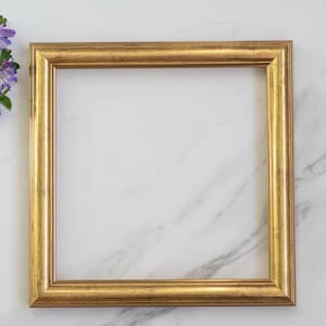Pode incluir: Uma moldura quadrada com acabamento dourado metálico e uma superfície texturizada e desgastada. A moldura apresenta um perfil escalonado de vários níveis com bordas arredondadas, criando um visual clássico. O tom dourado tem variações de cor.