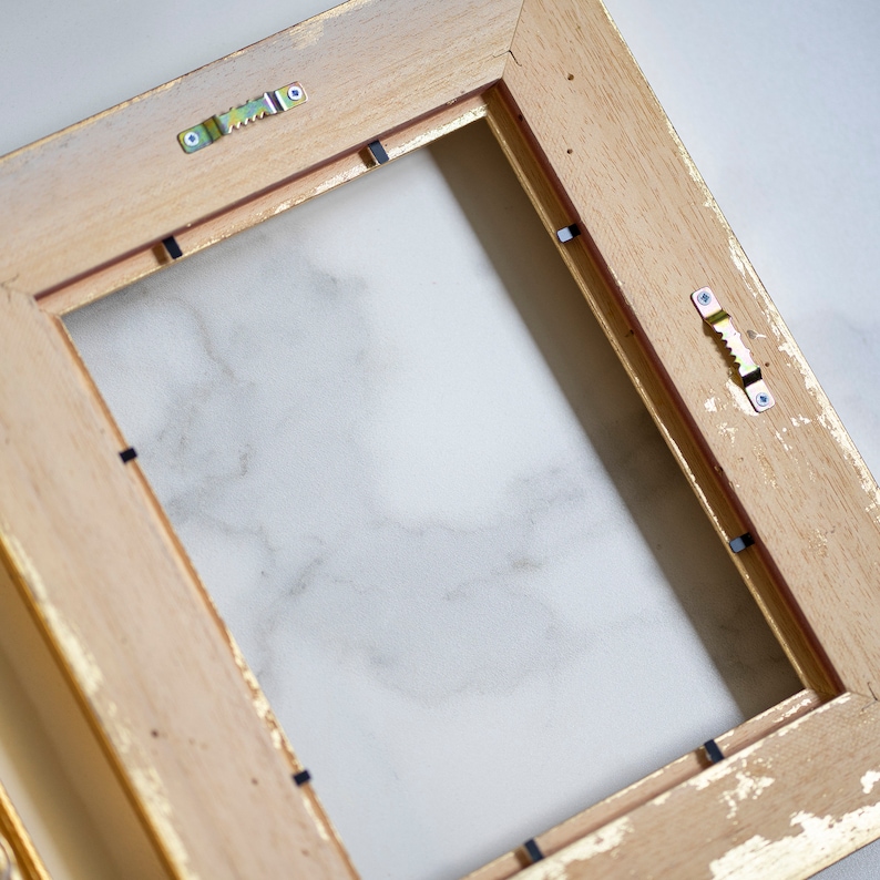 May include: A wooden picture frame with a gold finish. The frame has a white background and is ready to be used for a picture or artwork.