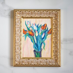 May include: A framed painting of a bouquet of tulips in a vase. The tulips are red, white, and yellow, and the vase is green. The painting is set against a light pink background.