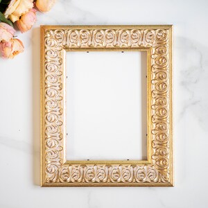 May include: A gold picture frame with an ornate design. The frame is empty and ready for a photo or artwork.