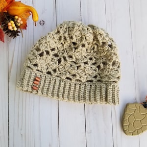 May include: A crocheted beige beanie with a lacy pattern and a brown button detail.