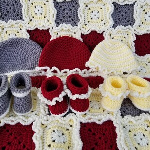 May include: A set of crocheted baby items in gray, red, and yellow. The set includes a blanket, three hats, and three pairs of booties.