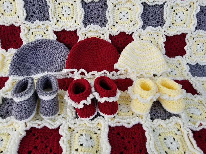 May include: A set of crocheted baby items in gray, red, and yellow. The set includes a blanket, three hats, and three pairs of booties.