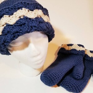 May include: A blue crocheted hat with a white and beige trim, and a pair of blue crocheted mittens with white and beige trim.