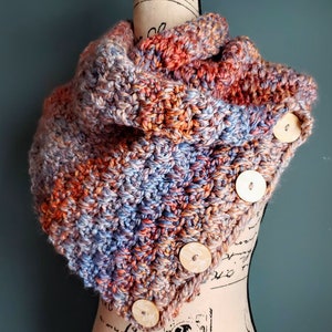 May include: A crocheted infinity scarf in shades of orange, pink, and blue with wooden buttons.