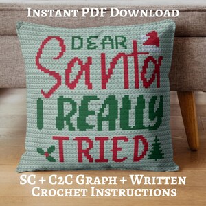 May include: A crocheted pillow with the text "DEAR SANTA I REALLY TRIED" in red and green. The pillow has a light blue background and includes a Santa hat, holly, and a Christmas tree graphic. The words "INSTANT PDF DOWNLOAD" and "SC + C2C GRAPH + WRITTEN CROCHET INSTRUCTIONS" are also visible.