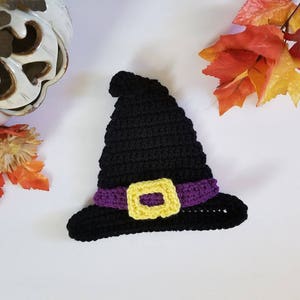 May include: A black crocheted witch hat with a purple and yellow buckle. The hat is a great accessory for Halloween costumes.