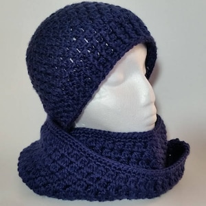 May include: A navy blue crocheted hat and matching scarf set. The hat is slouchy and the scarf is long and wide.