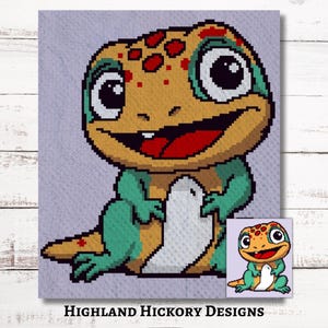 Könnte beinhalten: Ein Häkelmuster eines Cartoon-Eidechsen mit grünen und orangefarbenen Schuppen, roten Flecken und großen Augen. Die Eidechse hält ein weißes Ei in ihren Händen. Das Muster heißt "Highland Hickory Designs".