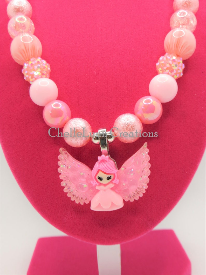 May include: Pink beaded necklace with a pink fairy charm. The necklace is made with iridescent and glitter beads.