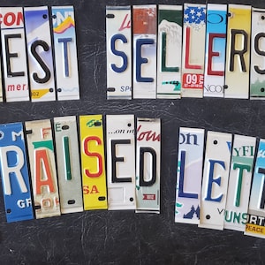May include: A collection of colorful, repurposed metal license plate segments arranged to spell out the words BEST SELLERS ALL RAISED LETTERS. Each letter is embossed and features various colors, fonts, and state-specific graphic designs.