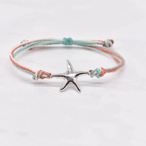Könnte beinhalten: Ein geflochtenes Armband in Weiß, Koralle und Türkis mit einem silbernen Seestern-Anhänger.