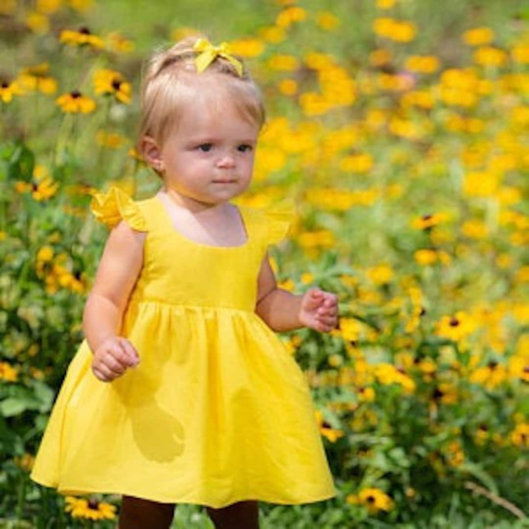 Baby girl wearing a summer dress with a large yellow bow on her head lying  on a bed Background available for text 27214418 Stock Photo at Vecteezy