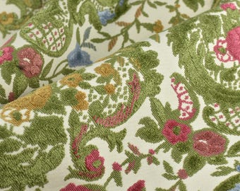 May include: A white fabric with a green, pink, and yellow floral pattern. The fabric has a raised texture and a soft, velvety feel.