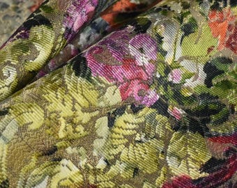 May include: A close-up of a fabric with a floral pattern. The fabric is a gold color with a textured surface. The flowers are pink, red, and green.