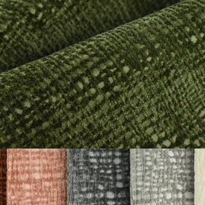 May include: Close-up of a green fabric with a textured pattern. The fabric has a subtle sheen and a soft, plush feel. The fabric is available in a variety of colours, including brown, pink, grey, and white.