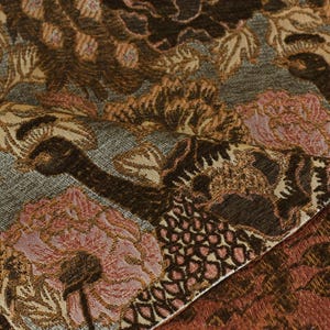 K&ouml;nnte beinhalten: Nahaufnahme eines Stoffes mit einem floralen Muster in Braun-, Rosa- und Graut&ouml;nen. Der Stoff hat eine strukturierte, gewebte Optik.