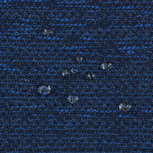 Puede incluir: Un primer plano de una tela azul oscuro con un tejido texturizado. La tela tiene un brillo sutil y está ligeramente arrugada. Hay varias pequeñas manchas blancas dispersas por la superficie.