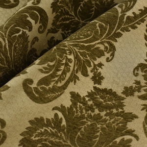 May include: Close-up of a fabric with a damask pattern. The fabric is a beige color with a dark green floral design.