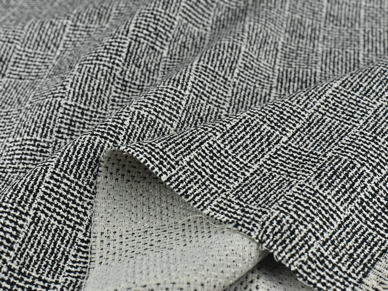 May include: Black and white herringbone patterned fabric with a subtle texture. The fabric is folded over, showing the reverse side.