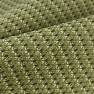 Può includere: Tessuto verde e bianco con un motivo geometrico. Il tessuto ha una superficie testurizzata e una leggera lucentezza.