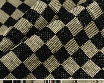 Puede incluir: Tela a cuadros negros y beige con textura tejida. La tela está doblada por la mitad, mostrando el patrón en ambos lados.