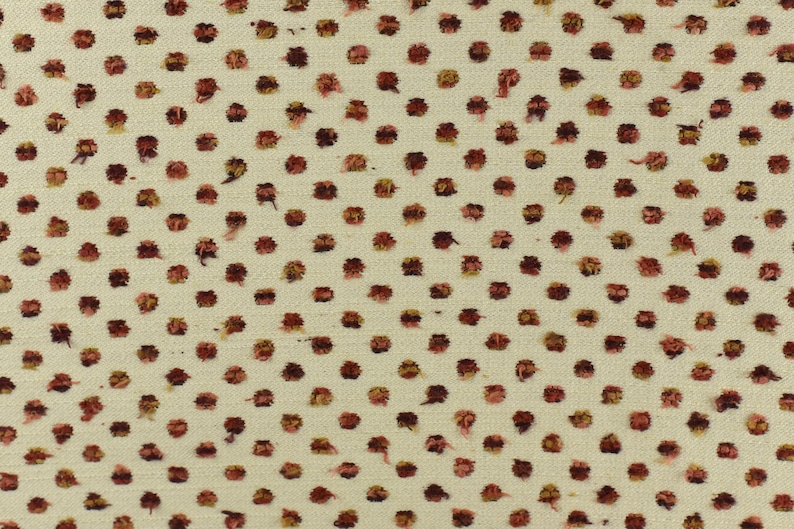 May include: A white fabric with a repeating pattern of small, brown and pink dots.