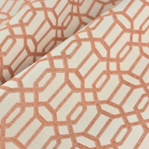May include: A close-up of a fabric with a geometric pattern. The fabric is white with a peach-colored geometric pattern.