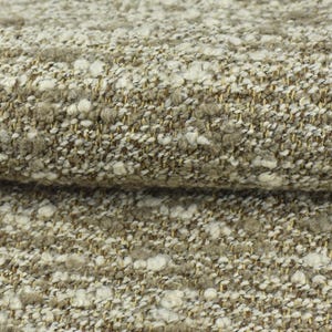 May include: Close-up of a textured fabric with a beige background and white flecks. The fabric has a subtle shimmer and a soft, fuzzy texture.