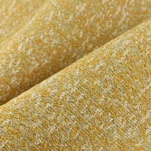 May include: Close-up of a yellow fabric with a white textured pattern. The fabric has a soft, fuzzy texture.