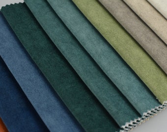 Op de afbeelding: Een close-up van stofstalen in verschillende tinten blauw, groen en bruin. De stof heeft een zacht, getextureerd oppervlak.