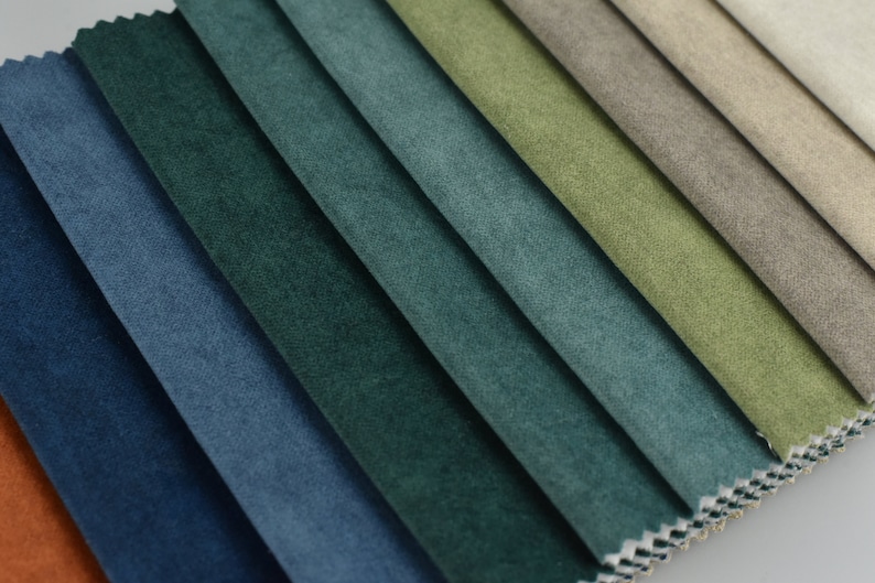 Puede incluir: Primer plano de muestras de tela en varios tonos de azul, verde y marr&oacute;n. La tela tiene una superficie suave y texturizada.