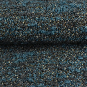 May include: Close-up of a textured fabric with a mix of teal, gray, and gold threads. The fabric has a nubby, woven appearance, with small, raised tufts of teal. The overall effect is a rich, dimensional textile.