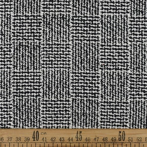 May include: Black and white woven fabric with a geometric pattern. The fabric is measured with a ruler in centimetres.