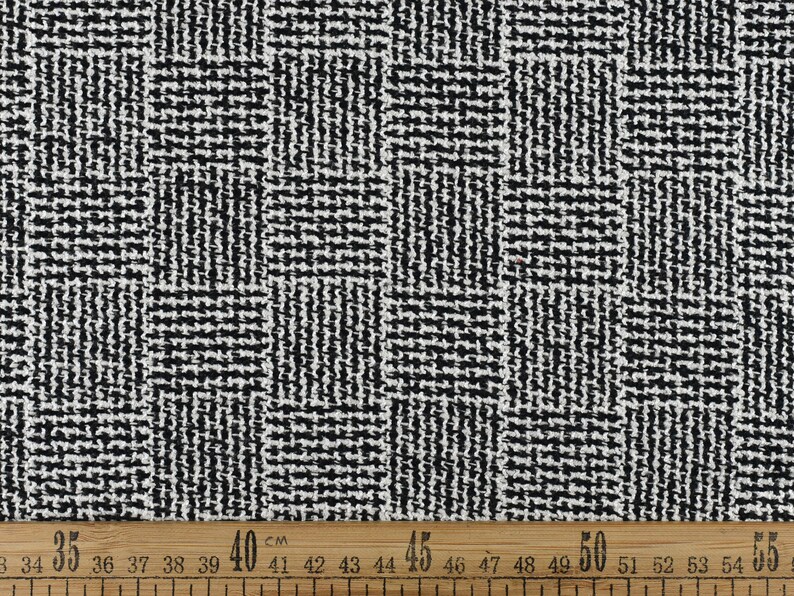 May include: Black and white woven fabric with a geometric pattern. The fabric is measured with a ruler in centimetres.