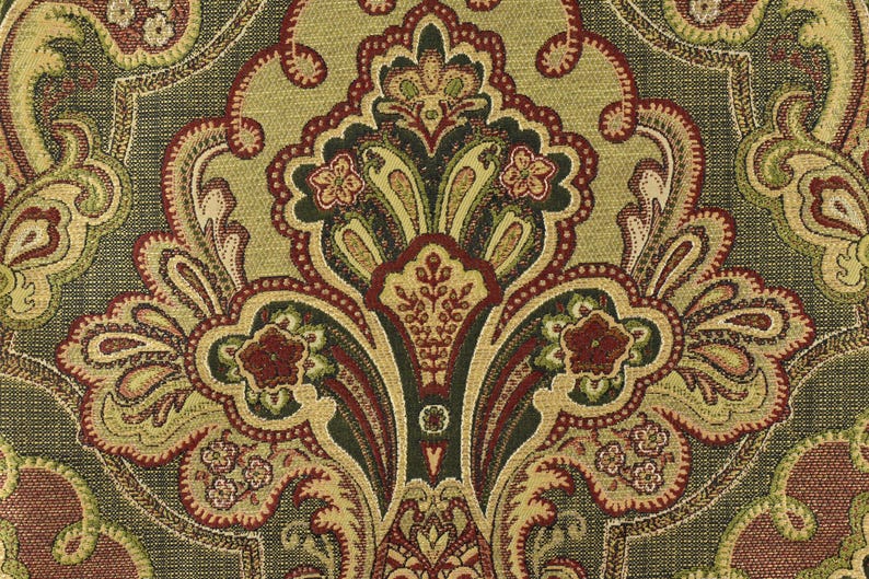 May include: Close-up of a decorative fabric with a detailed paisley pattern. The design features a central medallion with floral and scroll motifs in shades of olive green, burgundy, and gold against a dark green background.