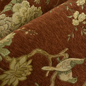 Puede incluir: Primer plano de una tela texturizada con un detallado estampado floral y de pájaros. La tela presenta un rico fondo marrón con diseños bordados en tonos verdes y crema, creando un aspecto clásico y elegante.