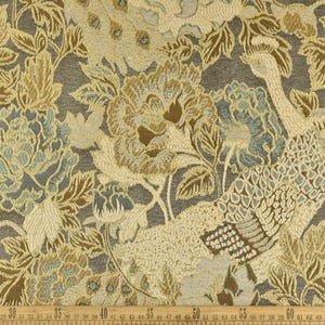 K&ouml;nnte beinhalten: Nahaufnahme eines Stoffes mit Blumen- und Vogelmuster. Der Stoff ist eine Tapisserie mit einer strukturierten Oberfl&auml;che. Die Farben sind Gold, Braun und Blau.