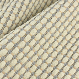 May include: Close-up of a woven fabric with a textured pattern. The fabric is a light beige color with a subtle gray and light brown pattern.