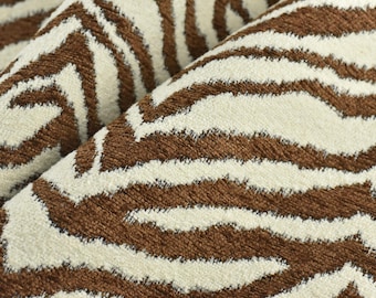 May include: Close-up of a brown and white zebra-print fabric. The fabric has a soft, plush texture and is perfect for upholstery or home decor projects.
