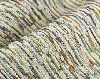 Op de afbeelding: Close-up van een geweven stof met een textuur, gestreept patroon in tinten beige, bruin, groen, blauw en oranje.