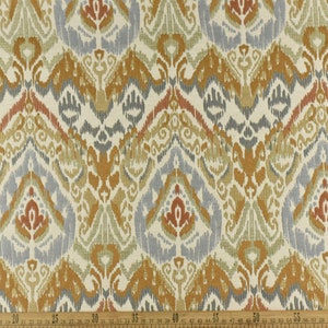 May include: A close-up of a fabric with a repeating pattern of blue, orange, and red ikat designs. The fabric has a white background and a subtle texture.