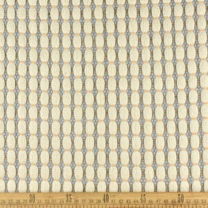 May include: Close-up of a white fabric with a woven pattern of small, light brown circles and thin, gray lines. The fabric is measured with a ruler in inches.
