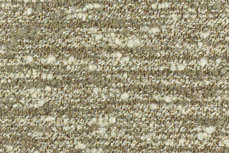 May include: Close-up of a textured fabric with a beige and white color scheme. The fabric has a woven appearance with small white flecks throughout.