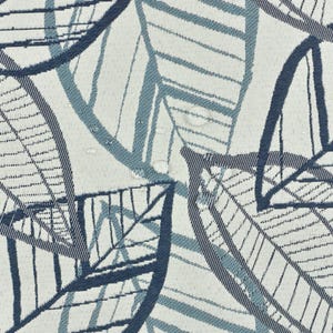 May include: A white fabric with a blue and gray leaf pattern. The leaves are stylized and have a woven texture.